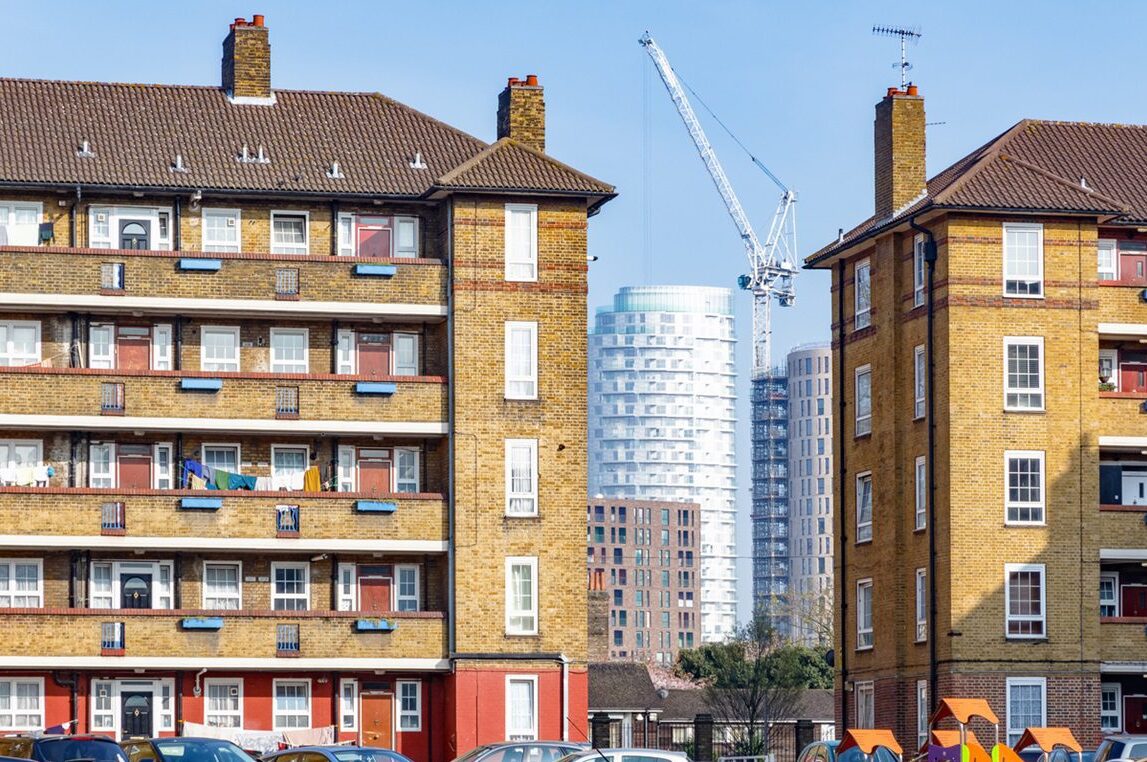 Council housing blocks contrasted with modern high-rise flats in the background in East London